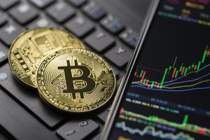 cryptocurrency coins on a computer keyboard next to a smartphone showing stocks why your business should accept cryptocurrency
