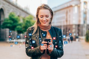 blond woman smiling down at smartphone as she receives several notifications concept: digital marketing budget email campaign bend oregon marketing